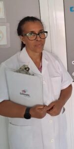 Healthcare professional in a white coat holding a clipboard with a SAHAL logo, standing in a clinic.