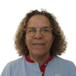 Close-up of a person with curly light brown hair, wearing round glasses and a light blue shirt with red trim.
