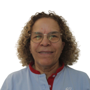 Close-up of a person with curly light brown hair, wearing round glasses and a light blue shirt with red trim.